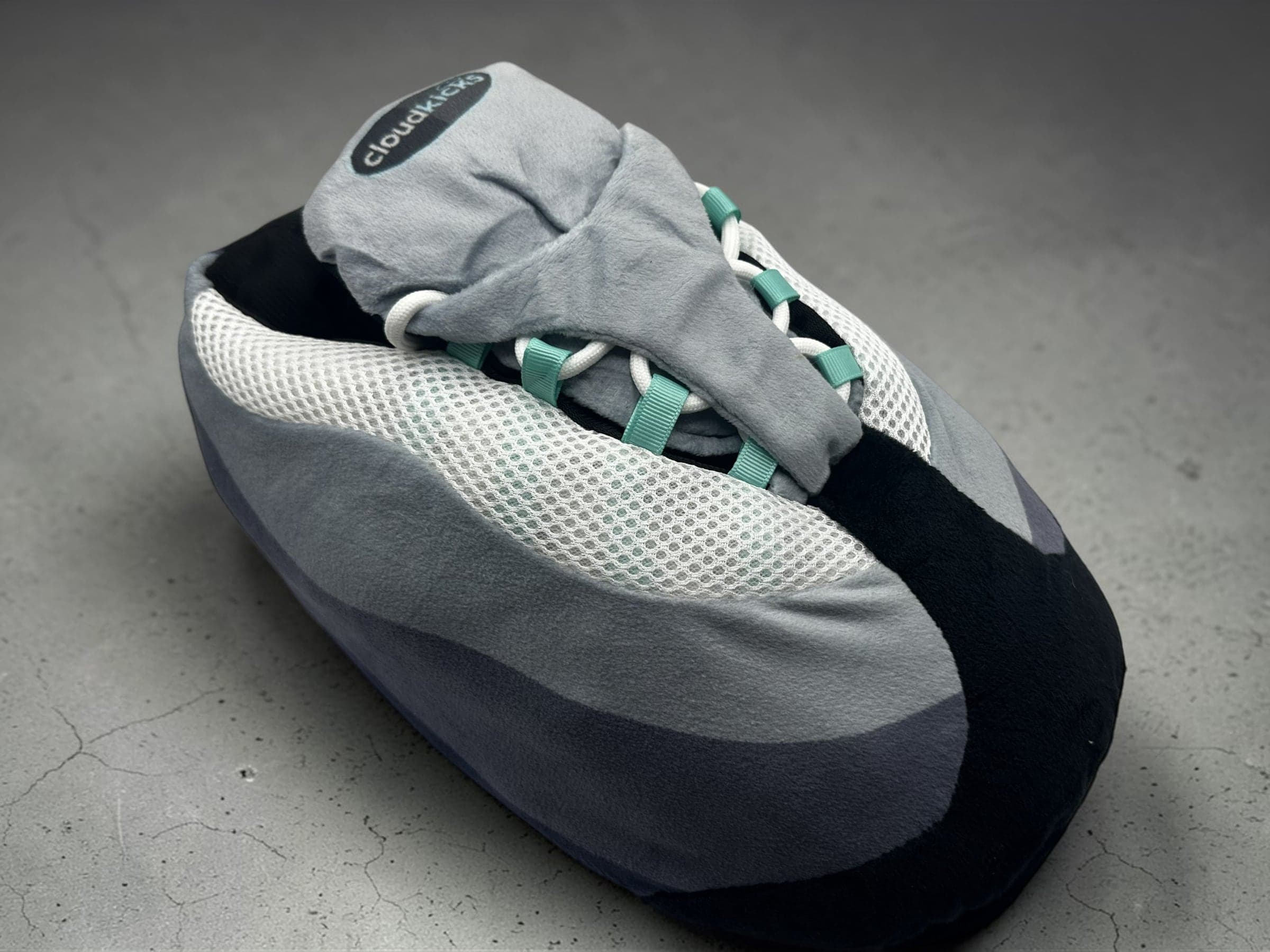 CloudKicks Air 110 Plush Slipper in Hyper Turquoise, three-quarter view on grey concrete