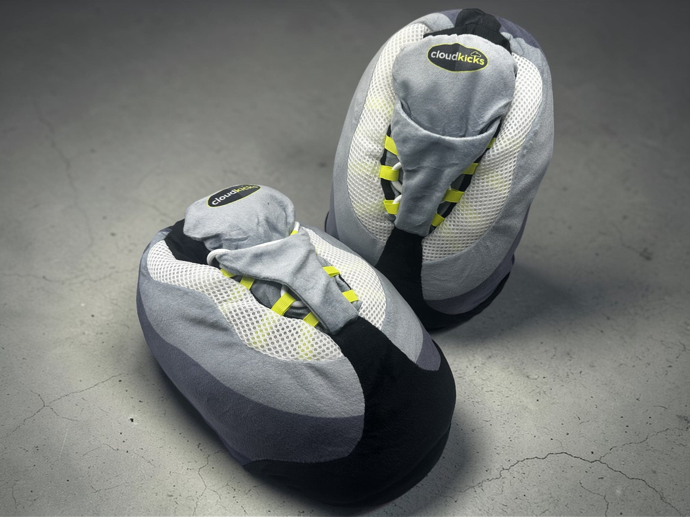 Pair of CloudKicks Air 110 Plush Slippers in OG Neon on grey concrete