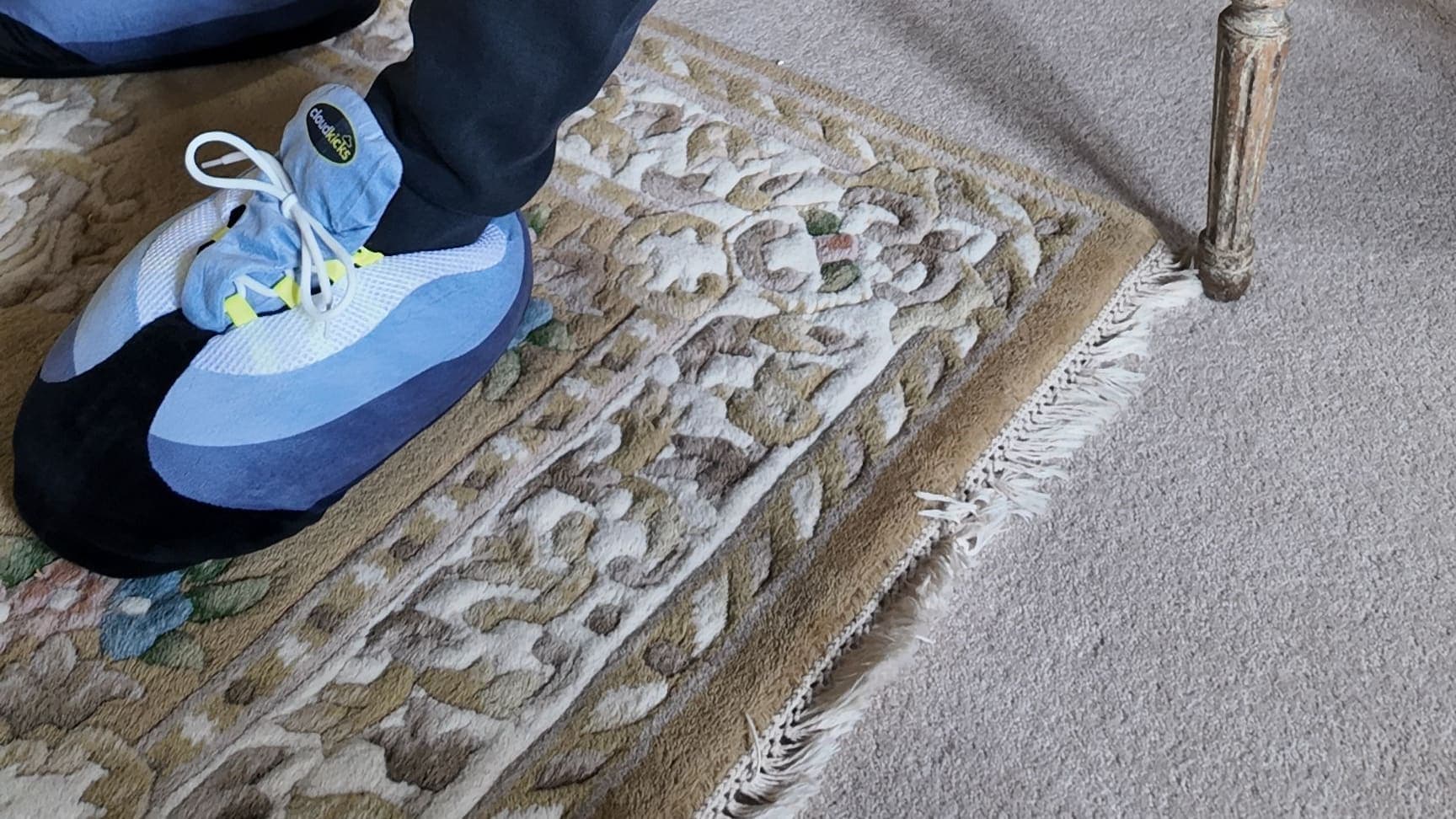 An OG Neon CloudKick on a patterned rug, navy joggers above