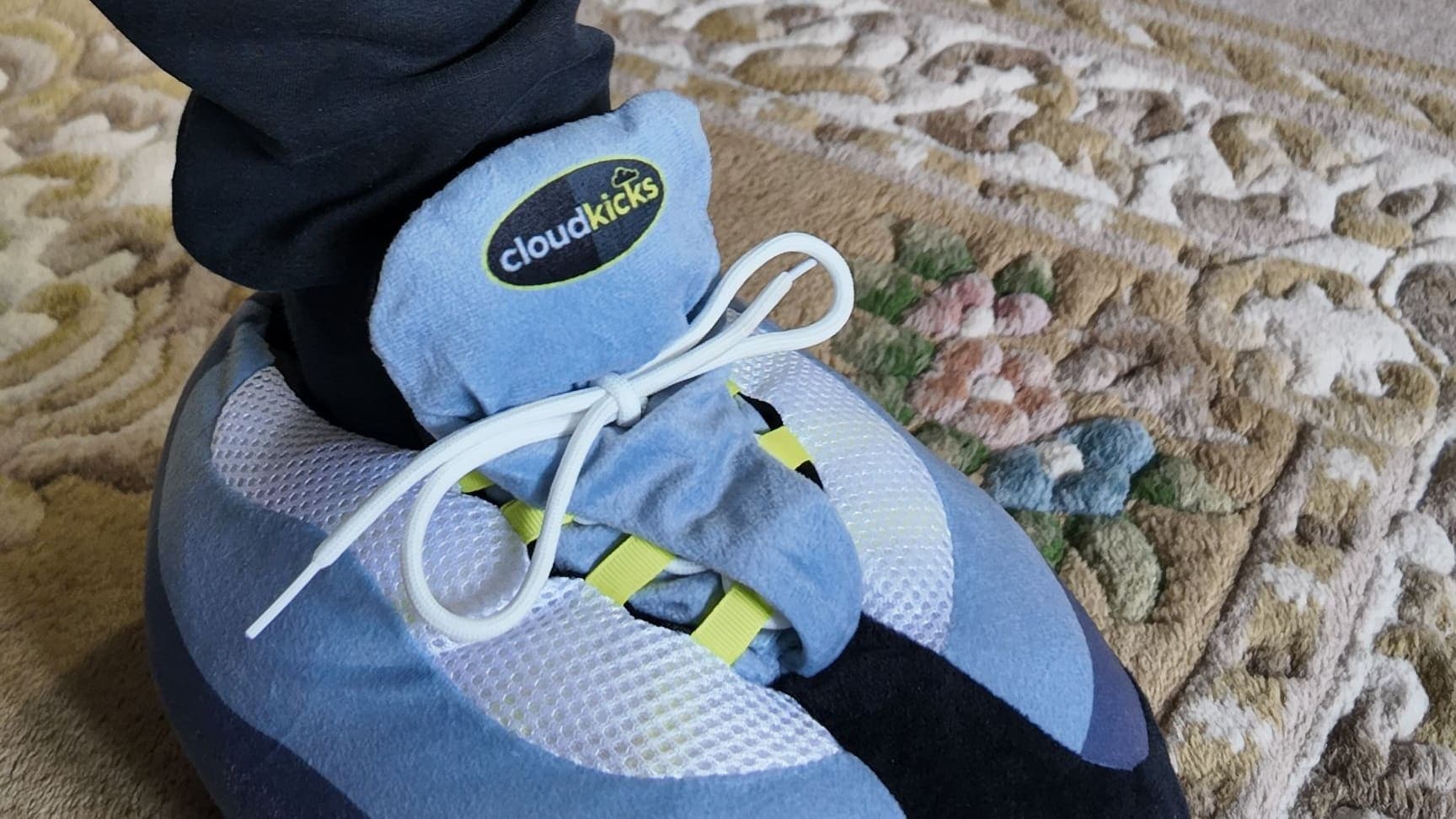 Close-up of an OG Neon CloudKick on a patterned rug, navy joggers above