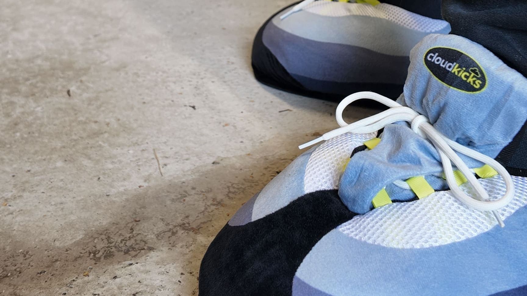 Close-up of OG Neon CloudKicks on a concrete garage floor, navy joggers above