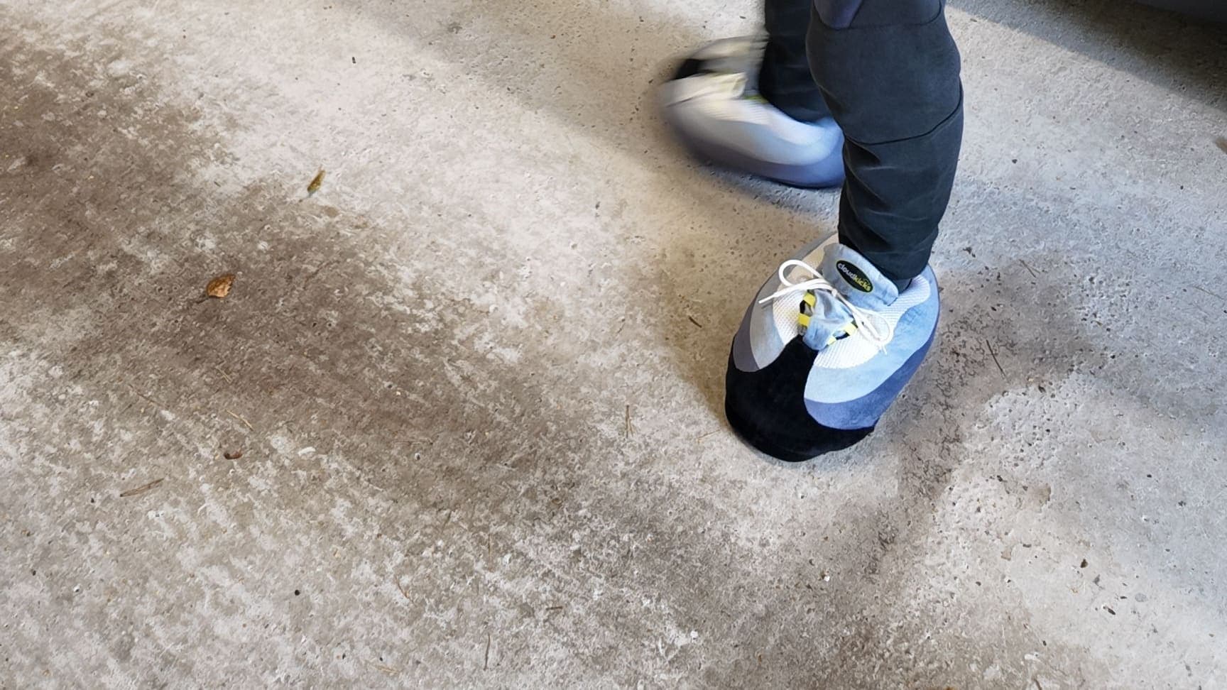 OG Neon CloudKicks mid-step on a concrete garage floor, navy joggers above