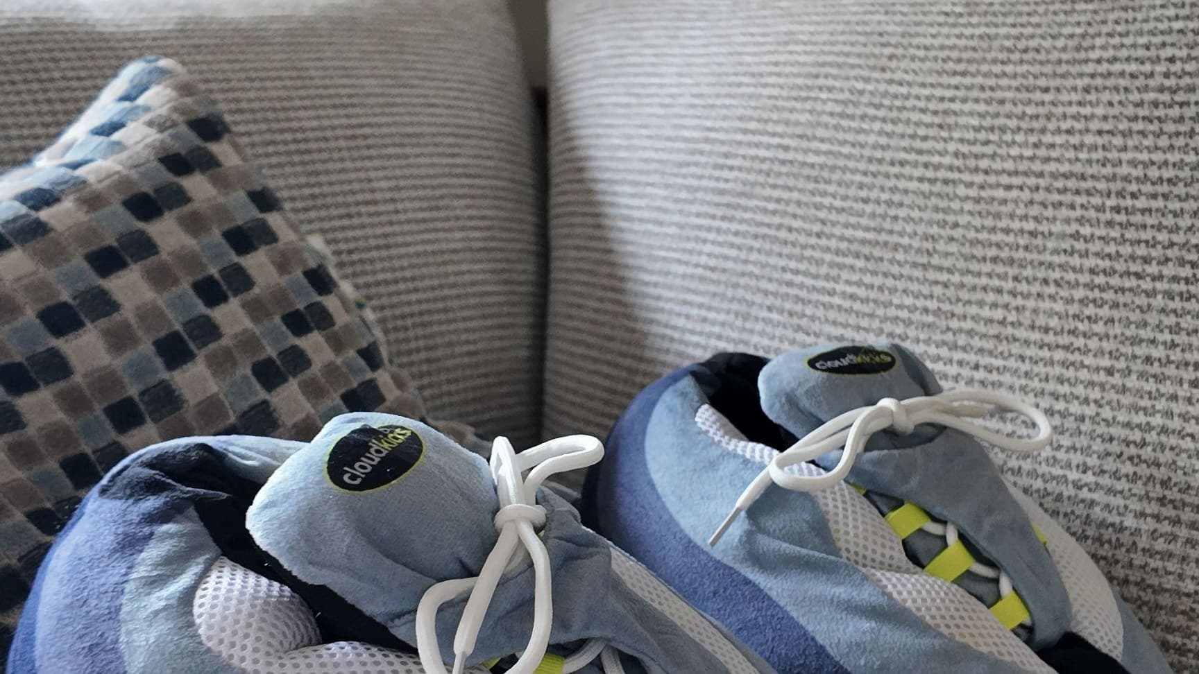A pair of OG Neon CloudKicks resting on the sofa cushions