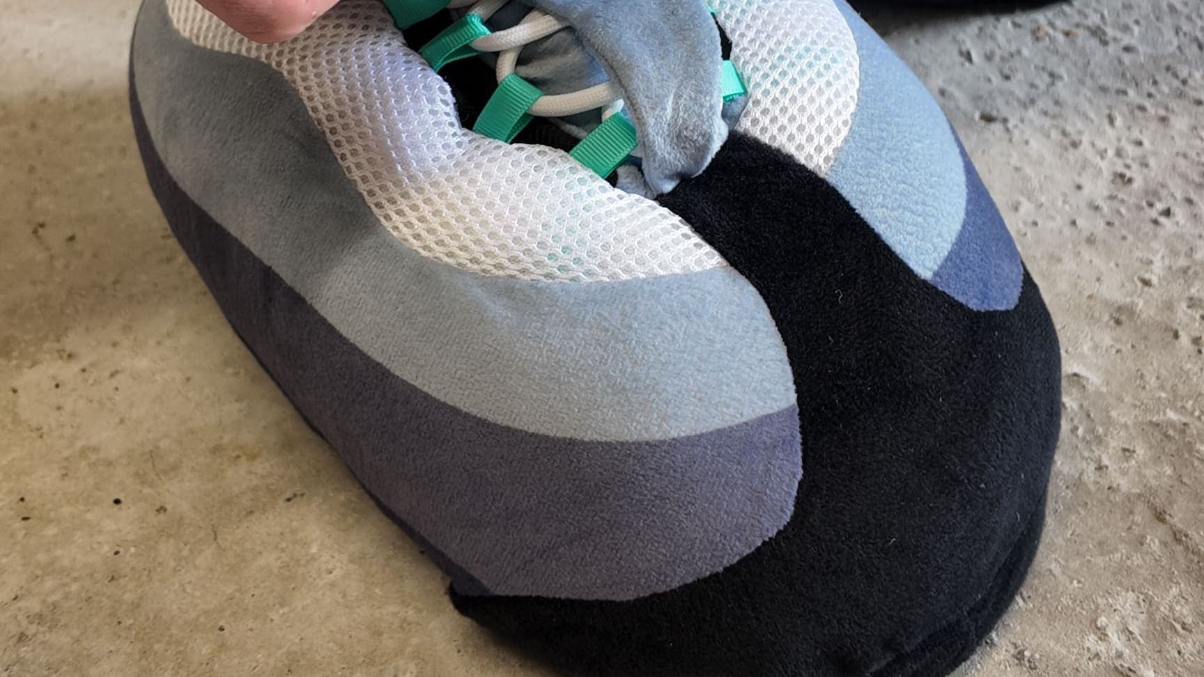 A hand at the laces of a Hyper Turquoise CloudKick on a concrete floor