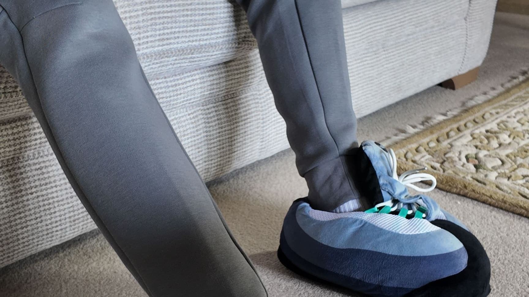 Perched on the edge of the sofa in grey joggers and Hyper Turquoise CloudKicks