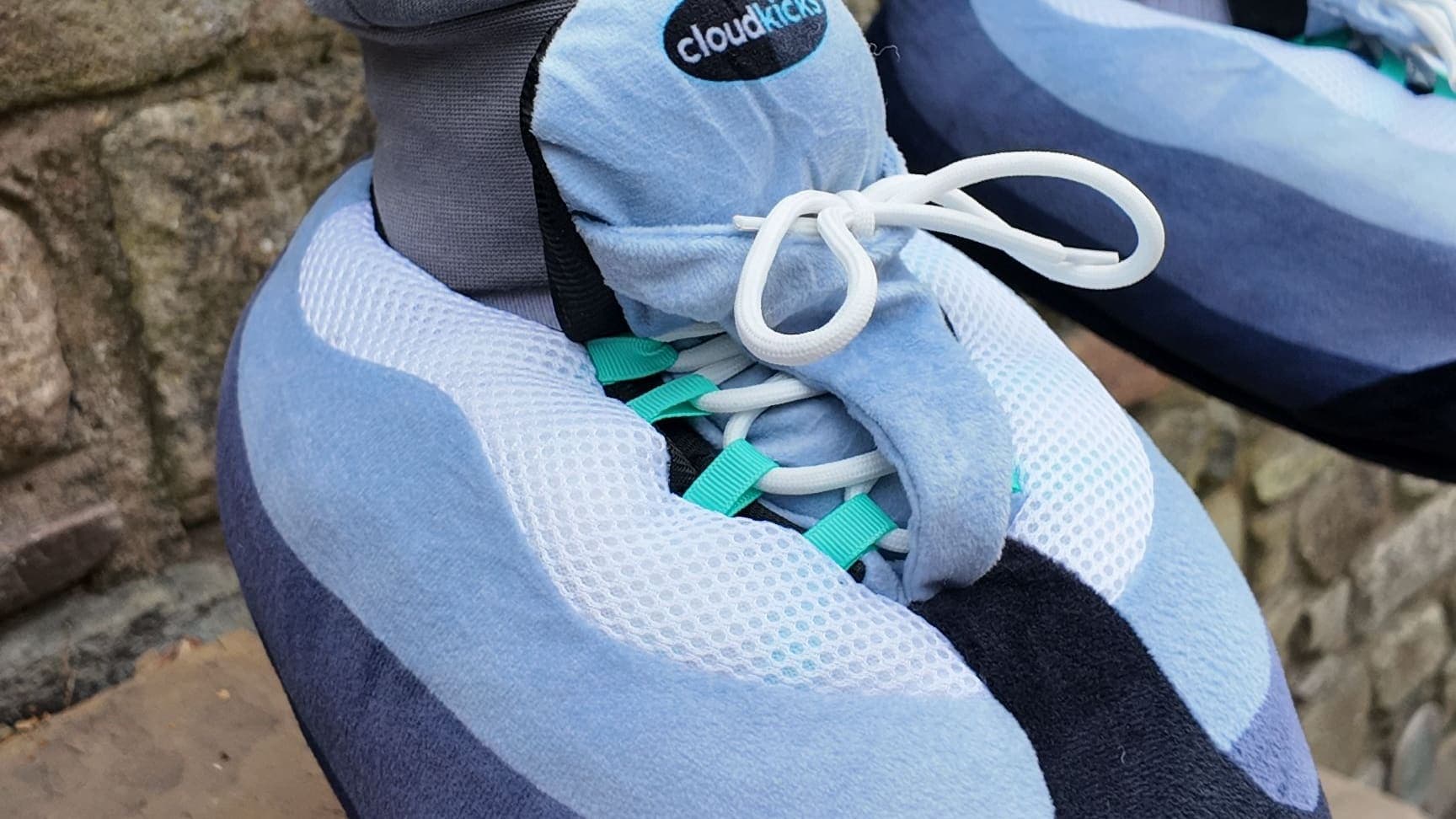 Close-up of a Hyper Turquoise CloudKick by an old stone wall, turquoise lace loops showing